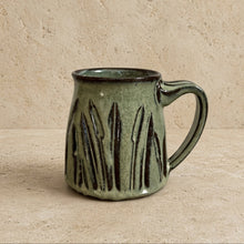 A handcrafted green ceramic handmade tapered mug with carved cattail pottery and textured vertical ridges