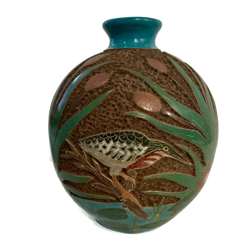 Carved ceramic vase with heron bird designs on a white background.
