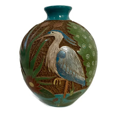 Carved ceramic vase with heron bird designs on a white background.