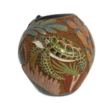 Carved ceramic vase with turtle design on a white background.