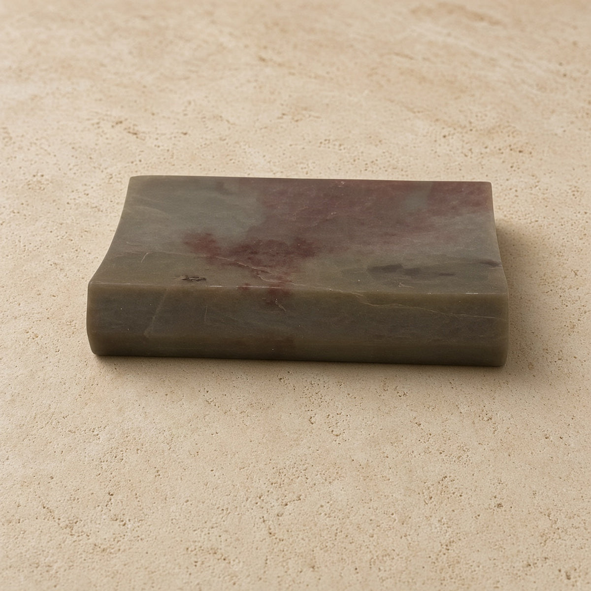 Carved soapstone rectangle concave soap dish with handmade marble soap look in muted green and reddish-brown hues