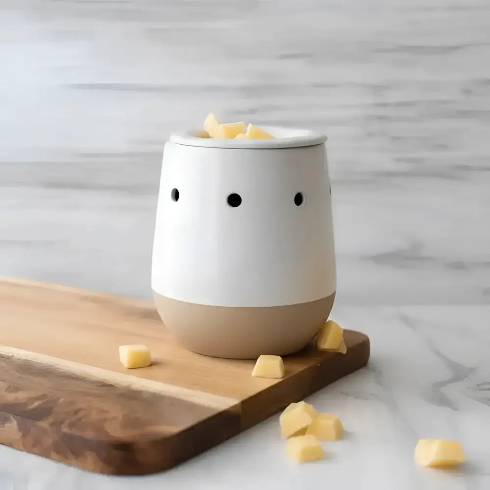 White ceramic electric wax warmer with black dot eyes and beige base filled with yellow favorite wax melts cubes