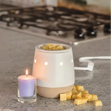 Ceramic electric wax warmer with matte white ceramic bowl and beige base filled with yellow favorite wax melts cubes