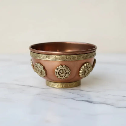 A small solid copper chakra cone incense bowl with gold-toned symbols and greek key patterns for meditation spaces