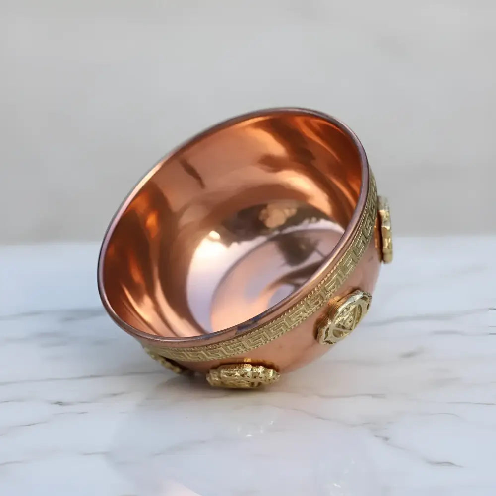 A small polished solid copper chakra cone incense bowl with gold bands and lion head motifs for meditation spaces and ritual practices