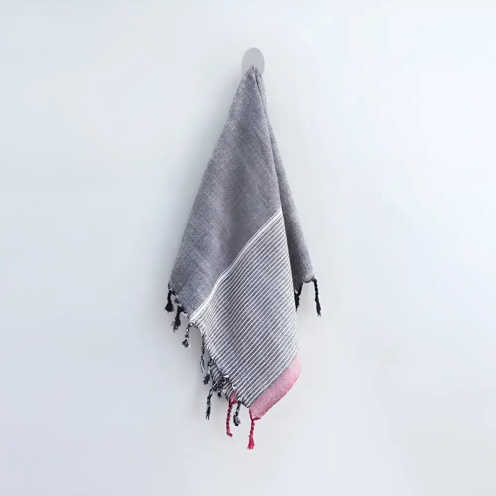 100% Turkish cotton towel that has been hand loomed in a flat weave and hand dyed in charcoal, off white and red colors.