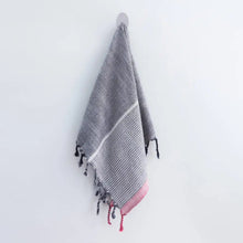 A charcoal and red striped handwoven cotton Turkish towel with tassels.