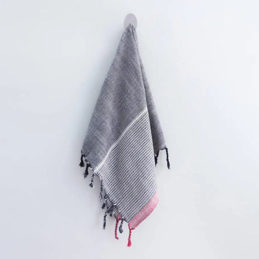 A charcoal and red striped handwoven cotton Turkish towel with tassels.