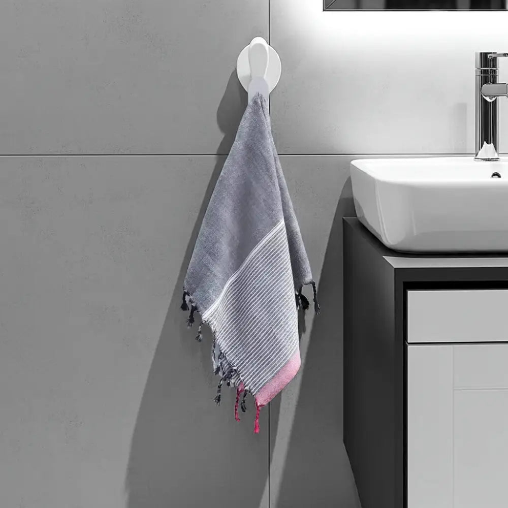 Gray and pink ruby striped Turkish hand towel with tassels hanging on a white hook