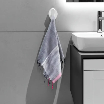 Gray and pink ruby striped Turkish hand towel with tassels hanging on a white hook