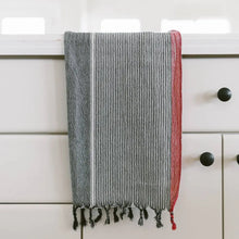 A charcoal and red striped handwoven cotton Turkish towel with tassels.