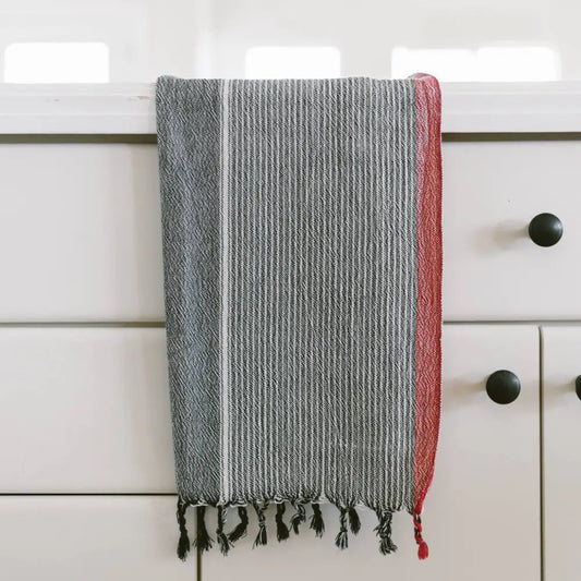 A charcoal and red striped handwoven cotton Turkish towel with tassels.