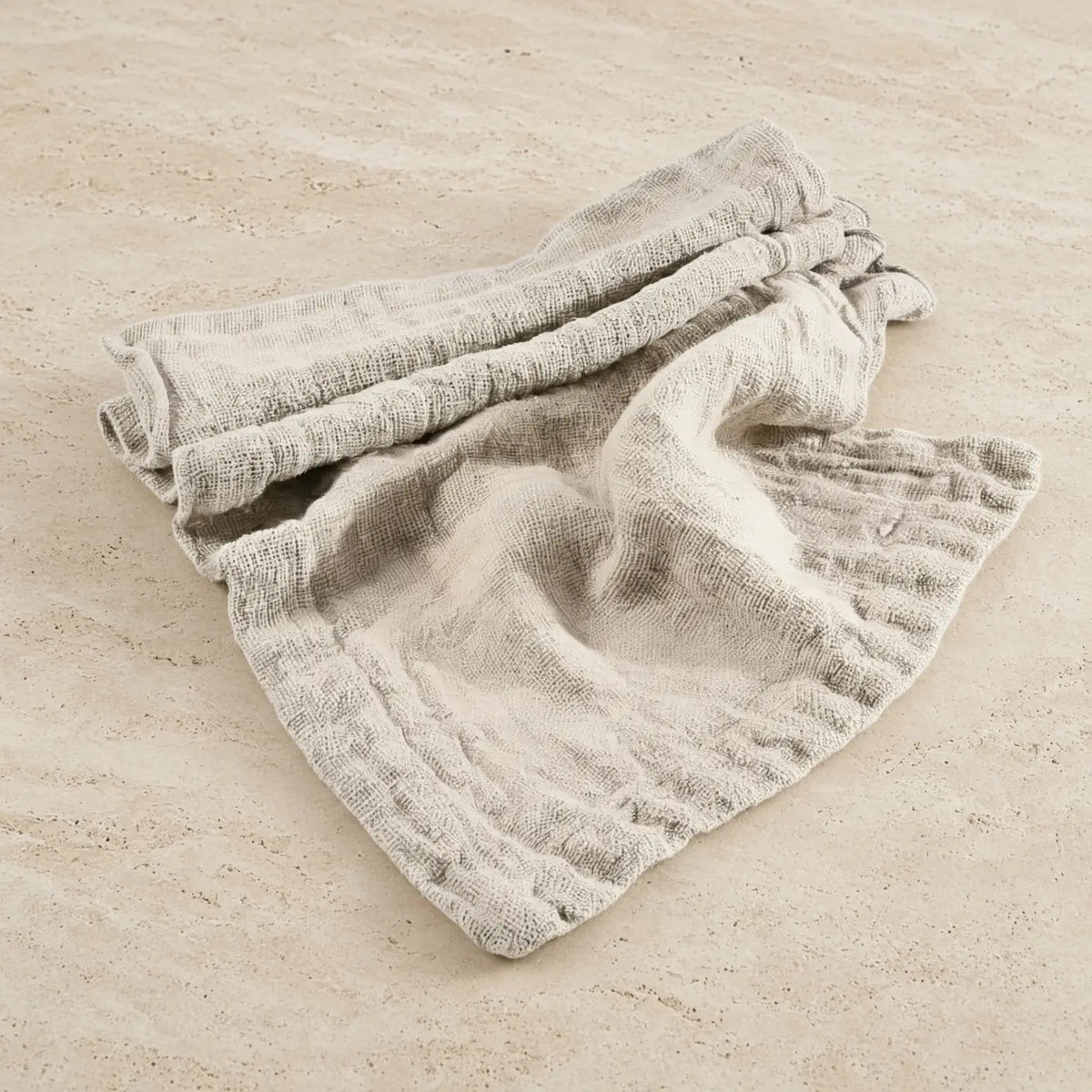 A soft light gray chunky linen table runner with a ribbed weave and frayed edges hand loomed for rustic dining decor