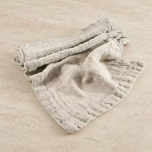 A soft light gray chunky linen table runner with a ribbed weave and frayed edges hand loomed for rustic dining decor