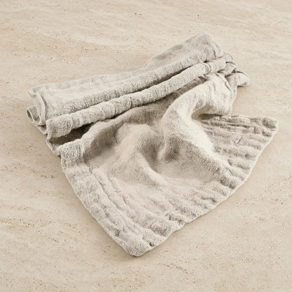 A soft light gray chunky linen table runner with a ribbed weave and frayed edges hand loomed for rustic dining decor