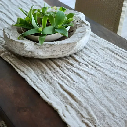 A textured beige table runner on a dark brown table.