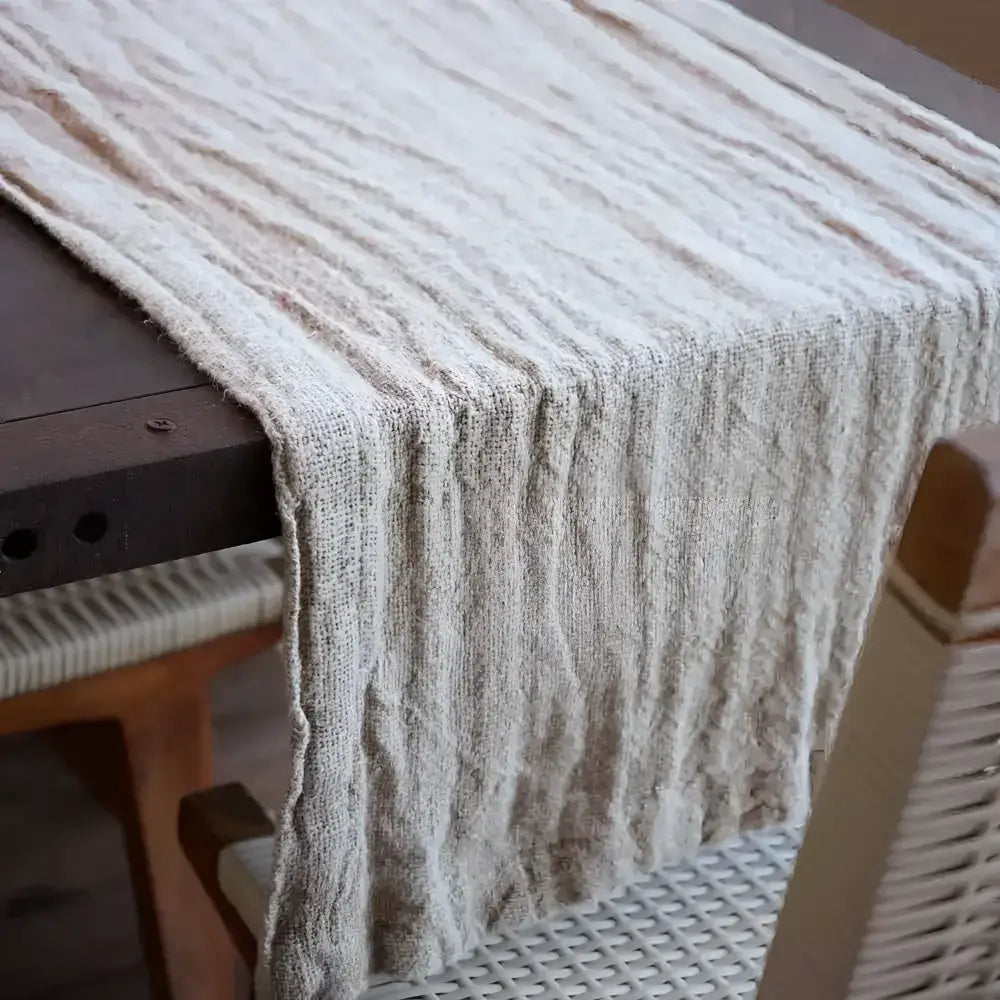 Table runner in textured linen hanging off of table.