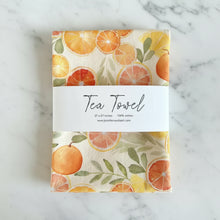 A cream-colored handmade tea towel with watercolor citrus slices perfect for any citrus lover kitchen decor