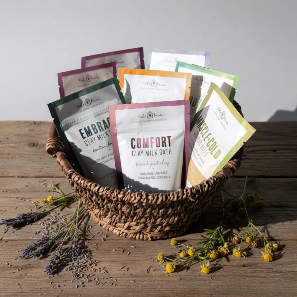 A woven brown basket filled with colorful clay milk bath packets featuring australian sandalwood and ylang ylang scents