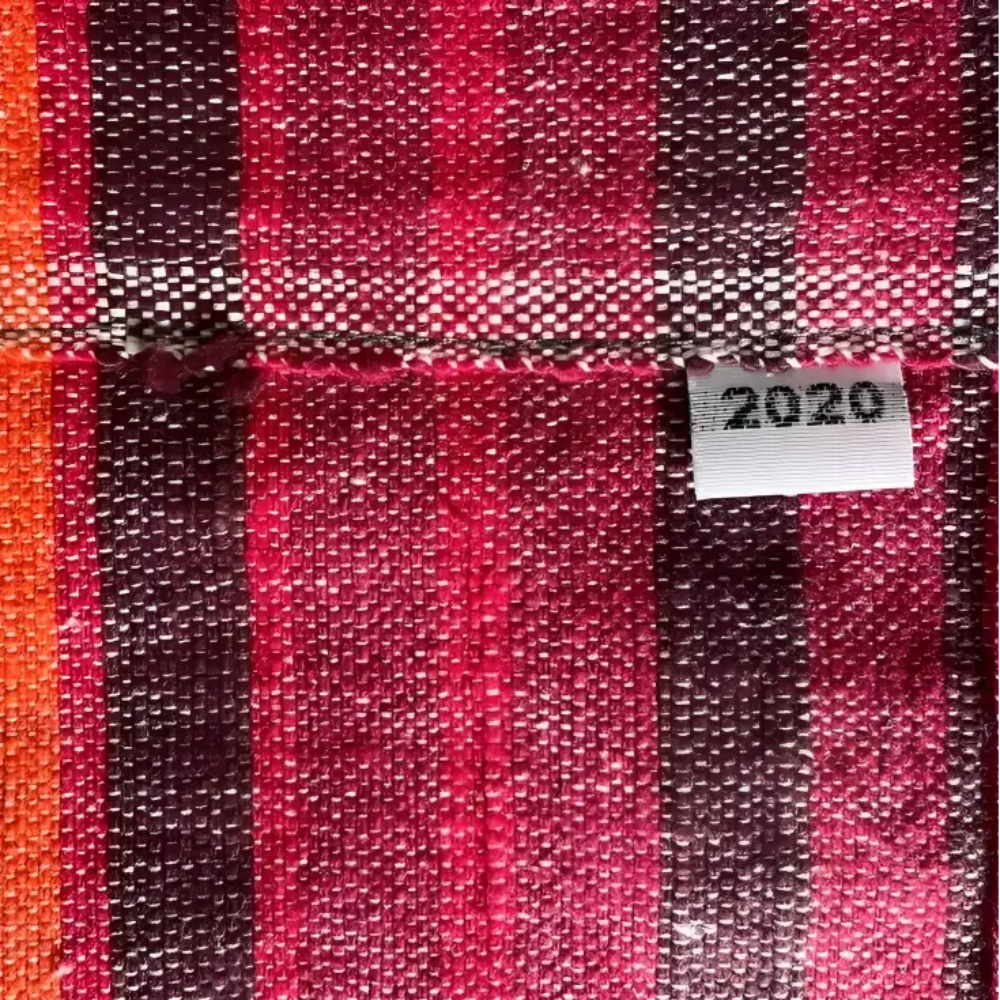 A handmade climate warming ethiopian table runner with bold red orange and dark brown woven vertical stripes