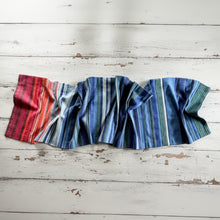 A handmade climate warming table runner with bold vertical stripes in red orange blue and green