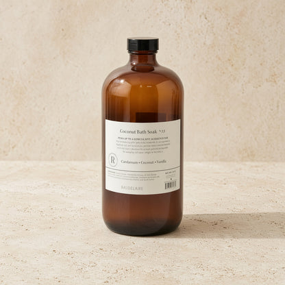 A sleek amber glass bottle with black cap labeled coconut bath soak by baudelaire replenishing 40oz for skin texture