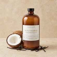 An amber glass bottle of baudelaire replenishing 40oz coconut bath soak with black cap beside coconut and vanilla beans for skin texture