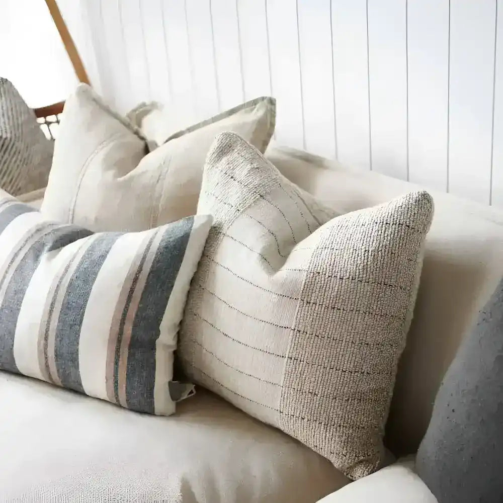 Textured pillow in natural color with black stripes on a sofa.