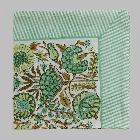 A cotton napkin with traditional Indian block print designs in green and brown.