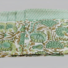 A cotton napkin with traditional Indian block print designs in green and brown.