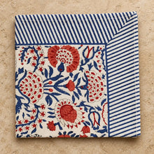 Cotton block print cotton napkins with vibrant red and blue floral pattern and navy striped border on off-white background