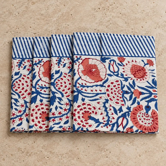 Set of four white cotton napkins with vibrant red and blue floral patterns and striped border in traditional indian block print style