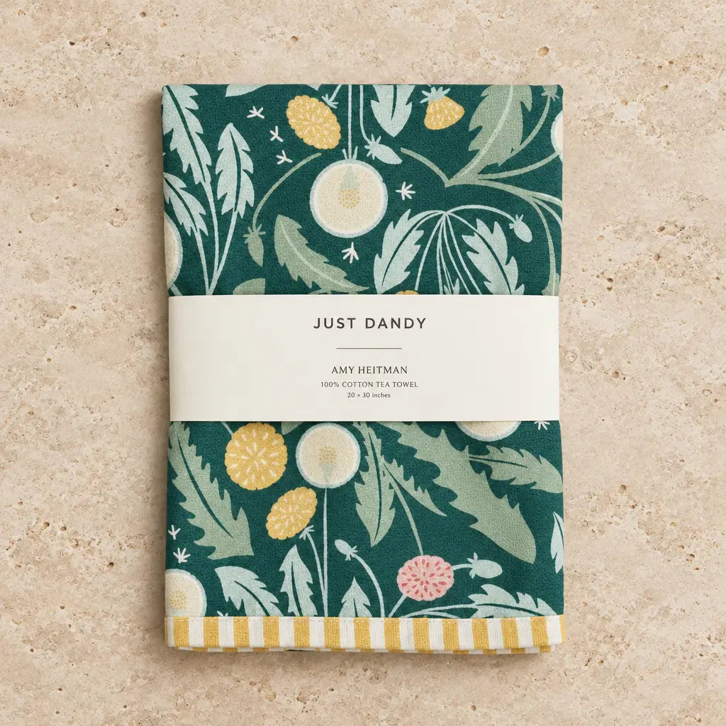 Folded dark green cotton tea towel with soft fabric and dandelion motif featuring yellow pink flowers and light green leaves
