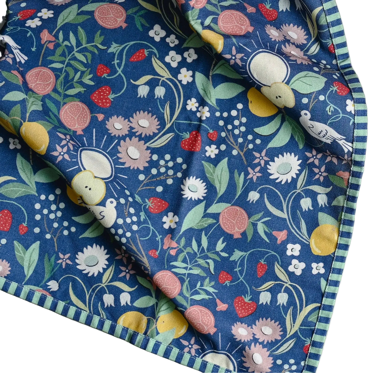 A navy blue cotton tea towel with charming striped edges featuring fruit flowers and birds in pastel hues
