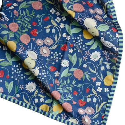 A navy blue cotton tea towel with charming striped edges featuring fruit flowers and birds in pastel hues