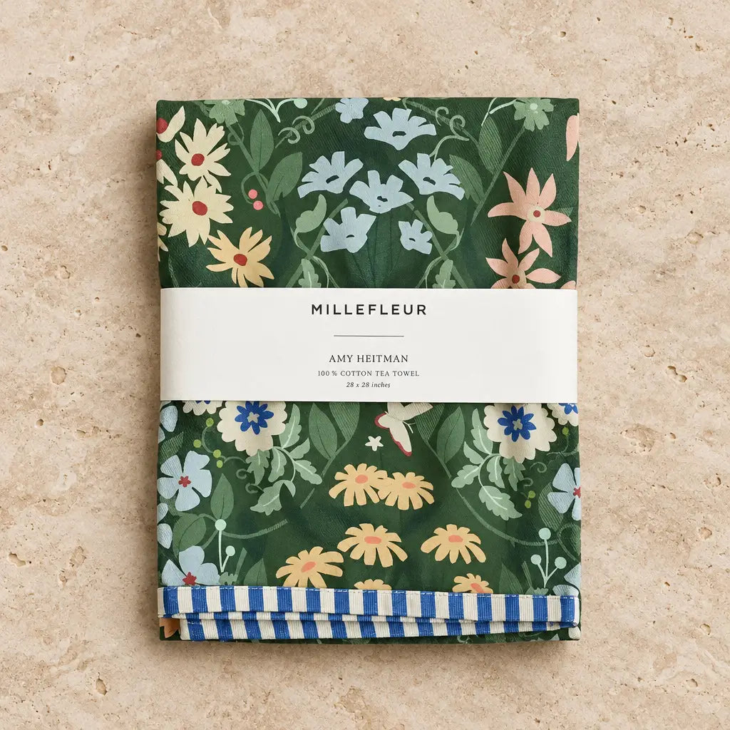 Folded dark green cotton tea towel with vibrant millefleur towel floral pattern and blue white striped border garden charm