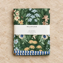 Folded dark green cotton tea towel with vibrant millefleur towel floral pattern and blue white striped border garden charm