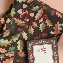 Cotton tea towel with whimsical leaf illustrations and cheerful striped edges features dark brown wrapping paper design