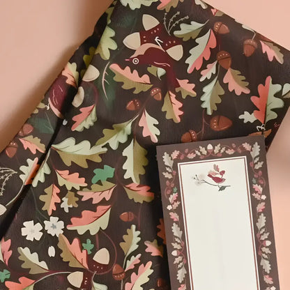 Cotton tea towel with leaves features a dark brown fabric and whimsical autumn oak leaf and acorn pattern