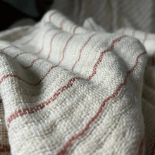 An off-white colored throw blanket with copper stripes.