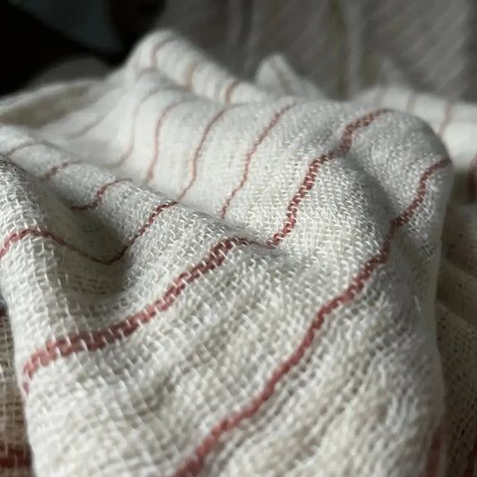 An off-white colored throw blanket with copper stripes.
