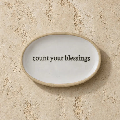 White ceramic trinket dish with beige rim and uplifting message count your blessings for daily reminders