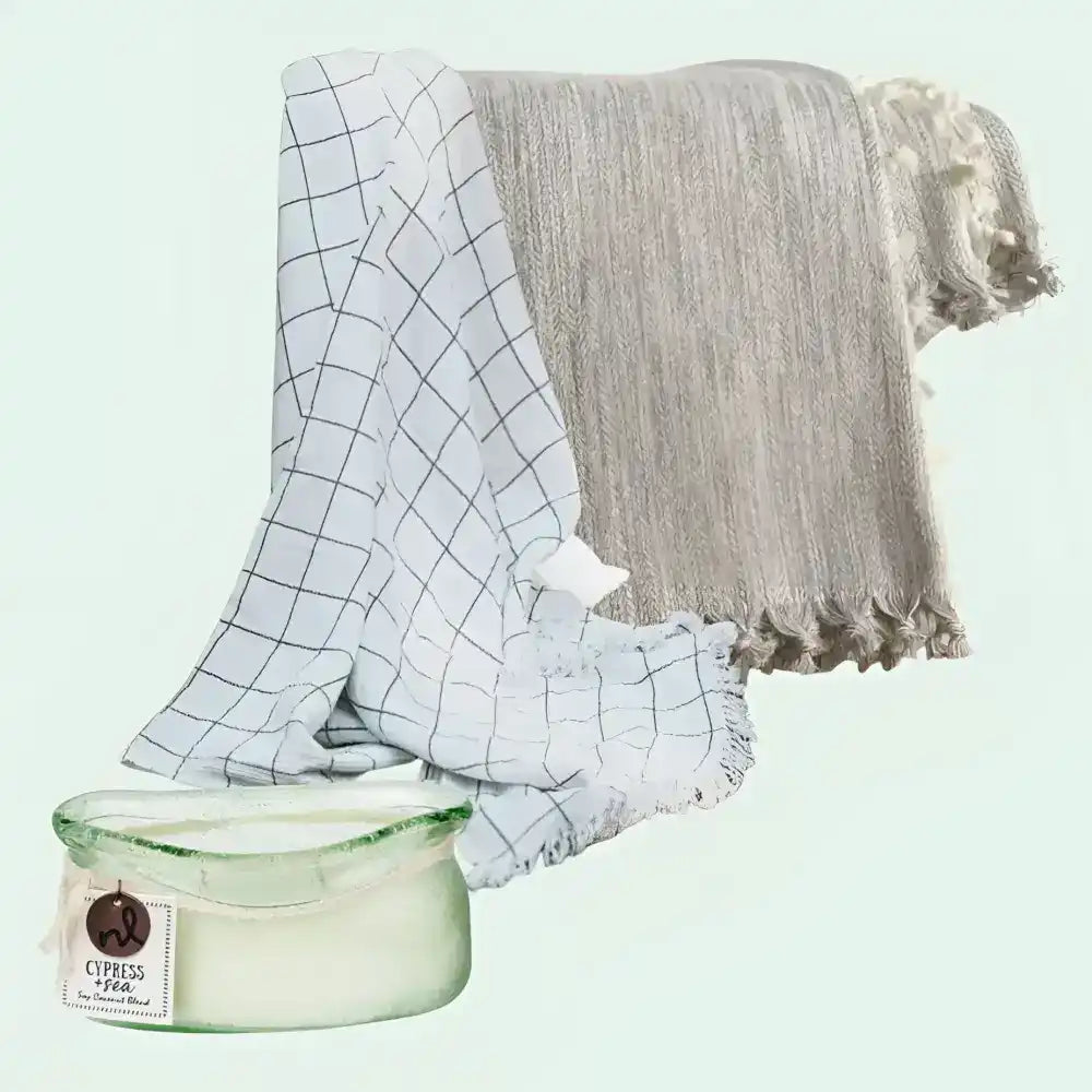 Two blankets, one checkered and one textured, draped next to a green container on a light blue background.