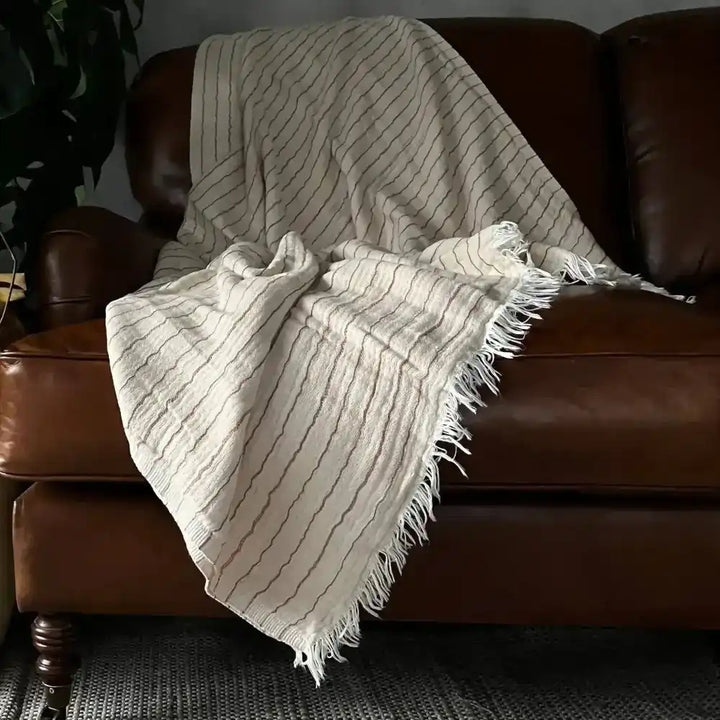 An off-white throw blanket with copper stripes.