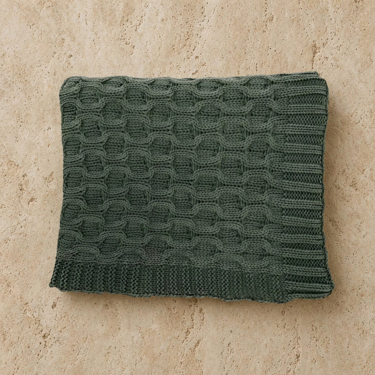 A dark green curvy green throw cable knit with a textured interwoven pattern made of soft washed cotton throw