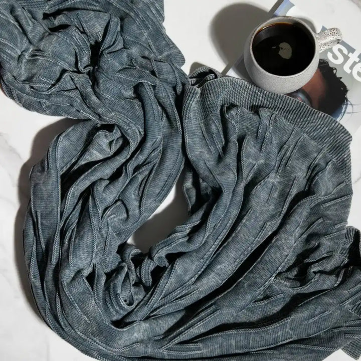 A throw blanket featuring a smooth, monochromatic textural knit in denim blue colors.