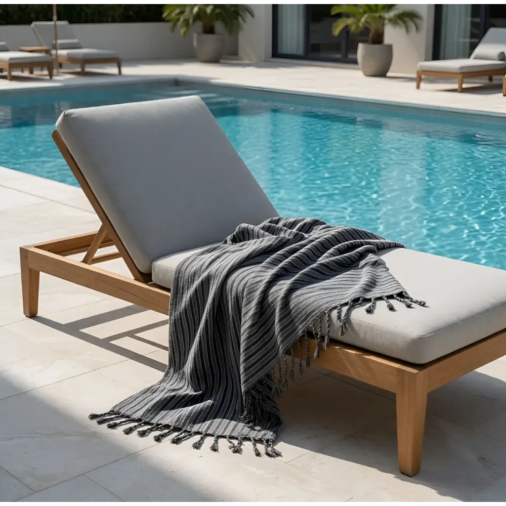Gray striped dark stripes towel with tassels handmade turkish towels draped on wooden lounge chair by the pool
