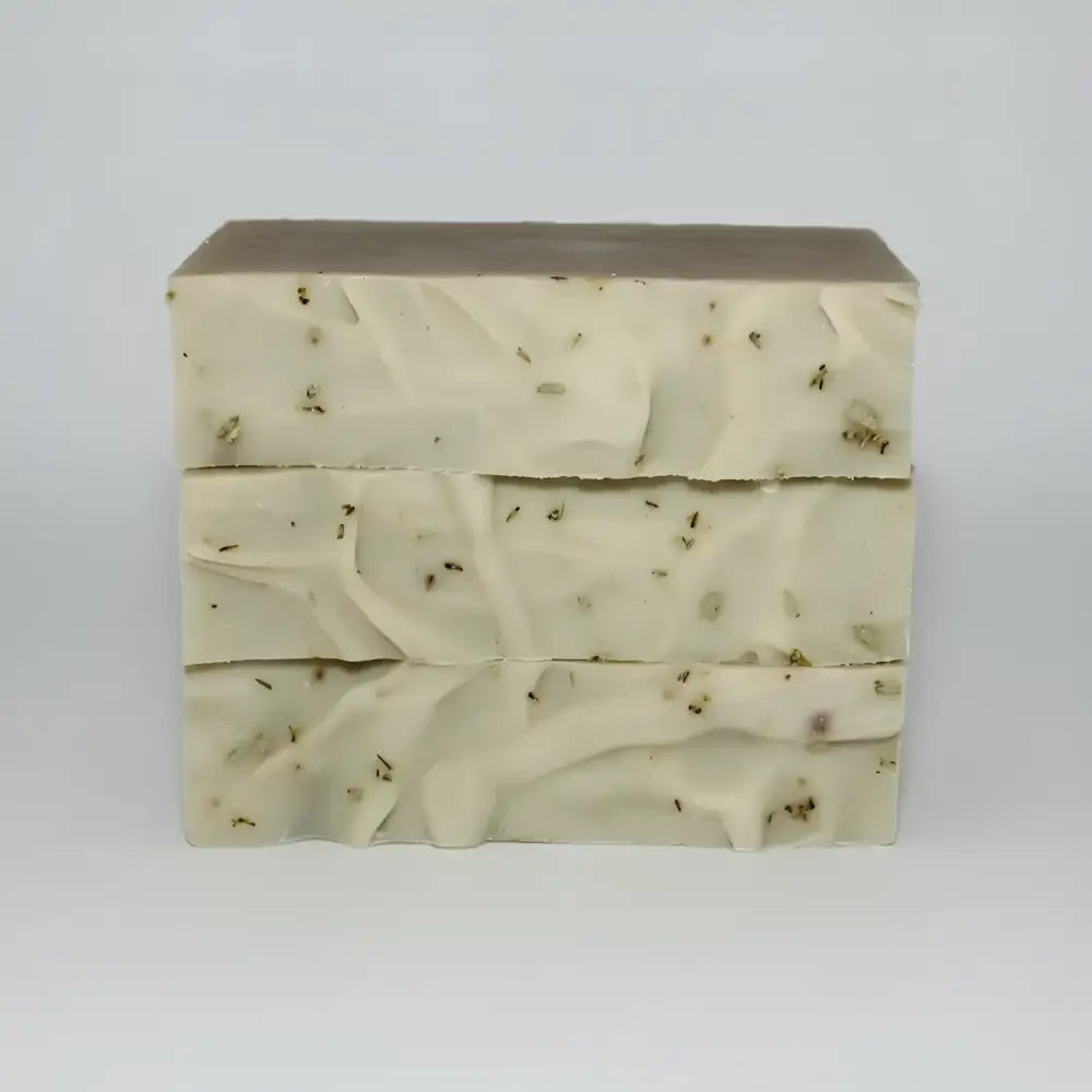 Three stacked bars of creamy off-white desert sage soap with certified organic essential oils and botanical fragments