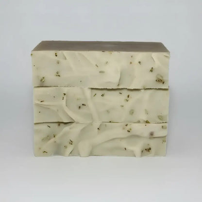 Three stacked bars of creamy off-white desert sage soap with certified organic essential oils and botanical fragments