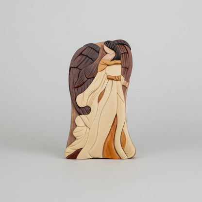 A wooden angel wall hanging with layered carved wings and robes in natural tones in a keepsake gift box by carver dan